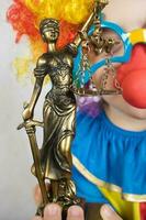 statua di themis nel il mano di cinque anni vecchio bambino vestito nel clown costume. foto