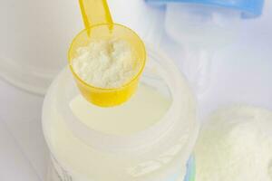 artificiale polvere latte nel un' misurazione plastica cucchiaio. foto