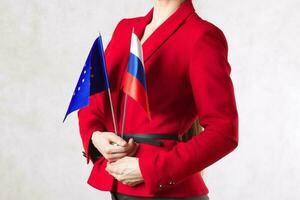 un' giovane donna fra 30 e 40 anni vecchio hold Due bandiere di Unione Europea e Russia. foto