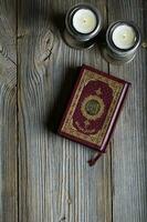 Corano e candele su un' di legno superficie. foto
