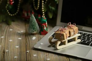 piccolo di legno slitta con Natale regali su un' il computer portatile. foto