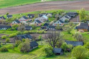 panoramico aereo Visualizza di eco villaggio con di legno case, ghiaia strada, giardini e frutteti foto