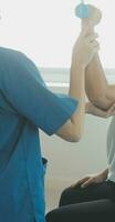fisioterapista uomo dando esercizio con manubrio trattamento di braccio e spalla di atleta maschio paziente fisico terapia concetto foto