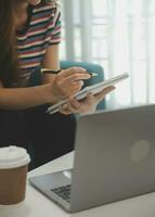 contento asiatico adolescente ragazza Tenere tampone computer aggeggio utilizzando digitale tavoletta tecnologia seduta su il divano a casa. sorridente giovane donna utilizzando app, shopping in linea, lettura notizia, navigazione Internet su divano foto