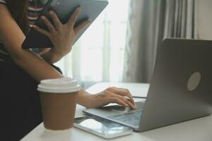 contento asiatico adolescente ragazza Tenere tampone computer aggeggio utilizzando digitale tavoletta tecnologia seduta su il divano a casa. sorridente giovane donna utilizzando app, shopping in linea, lettura notizia, navigazione Internet su divano foto