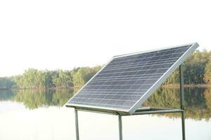 mini solare pannello o fotovoltaico In piedi con pioggia gocce , installato accanto il lago. concetto, rinnovabile energia, creare elettricità a partire dal naturale risorsa. alternativa energia energia per ambiente. foto