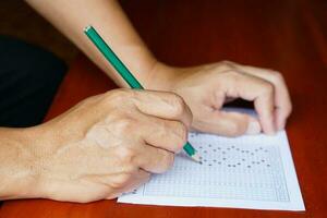 vicino su mano detiene matita per Scrivi su carta test. concetto, formazione scolastica. multiplo scelta visita medica, valutazione. scegliere e disegnare cerchio nel corretta Rispondere. scuola stile di vita. foto