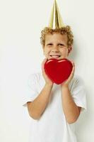 allegro ragazzo con un' berretto su il suo testa un' regalo scatola nel il modulo di un' cuore foto