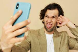 attraente uomo nel un' completo da uomo in posa emozioni guardare a il Telefono isolato sfondo foto