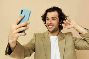 bello uomo con un' Telefono nel mano beige completo da uomo elegante stile stile di vita inalterato foto