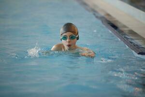 ragazzo nel un' nuoto berretto e nuoto occhiali nel il piscina. il bambino è impegnato nel il nuoto sezione. foto