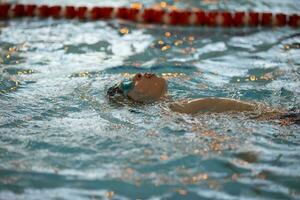 ragazzo nel un' nuoto berretto e nuoto occhiali nel il piscina. il bambino è impegnato nel il nuoto sezione. foto