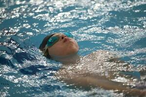 ragazzo nel un' nuoto berretto e nuoto occhiali nel il piscina. il bambino è impegnato nel il nuoto sezione. foto