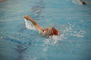 ragazzo nel un' nuoto berretto e nuoto occhiali nel il piscina. il bambino è impegnato nel il nuoto sezione. foto