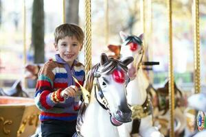 bello poco ragazzo è equitazione un' giostra. un' bambino su un' cavallo giostra. foto