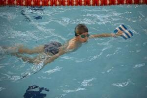 ragazzo nel un' nuoto berretto e nuoto occhiali nel il piscina. il bambino è impegnato nel il nuoto sezione. foto