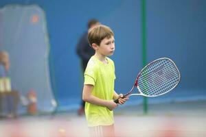 poco ragazzo con un' tennis racchetta. il bambino giochi tennis. foto
