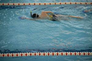 ragazzo nel un' nuoto berretto e nuoto occhiali nel il piscina. il bambino è impegnato nel il nuoto sezione. foto