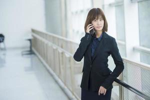 attraente donna d'affari asiatici utilizzando sullo smartphone fuori ufficio foto