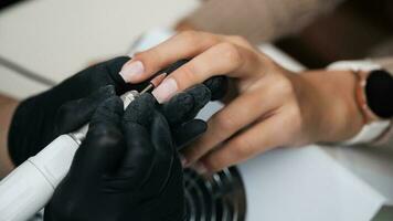 un' avvicinamento di un' manicure maestro in lavorazione il chiodo superficie con un' fresa su un elettrico macchina, rimozione sbavature. il concetto di un' professionale manicure salone foto