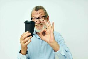 ritratto anziano uomo con un' nero bicchiere nel il suo mani un' bevanda isolato sfondo foto