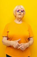 ritratto di un vecchio amichevole donna nel un' giallo maglietta in posa isolato sfondo foto