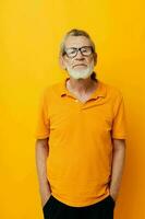 ritratto di contento anziano uomo con un' grigio barba nel bicchieri giallo sfondo foto