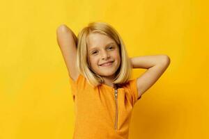 carino poco ragazza Sorridi mano gesti in posa casuale indossare divertimento giallo sfondo inalterato foto