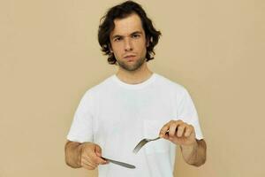 uomo nel un' bianca maglietta con coltello con forchetta isolato sfondo foto