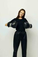 giovane bellissimo donna nel boxe guanti punch nel nero pantaloni e un' maglietta stile di vita inalterato foto