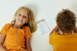 carino prescolastico bambini disegno nel i Quaderni dire bugie su il pavimento isolato sfondo inalterato foto