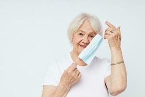 emotivo anziano donna medico maschera nel mano sicurezza isolato sfondo foto