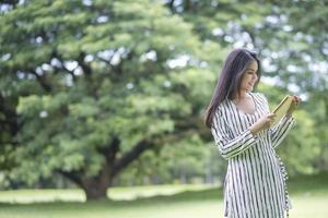 donna attraente che legge un libro nel parco foto