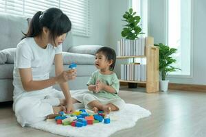 contento Asia madre giocare e imparare giocattolo blocchi con il poco ragazza. divertente famiglia è contento e eccitato nel il Casa. madre e figlia avendo divertimento la spesa tempo insieme. vacanza, attività, sviluppo foto