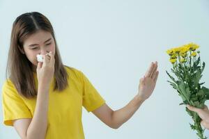 polline allergie, asiatico giovane donna starnuti nel un' fazzoletto o soffiaggio nel un' pulire, allergico per selvaggio primavera fiori o fiori durante primavera. allergico reazione, respiratorio sistema i problemi foto