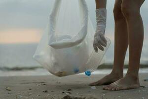 Salva oceano. volontario raccogliere su spazzatura spazzatura a il spiaggia e plastica bottiglie siamo difficile decomporsi impedire danno acquatico vita. terra, ambiente, greening pianeta, ridurre globale riscaldamento, Salva mondo foto