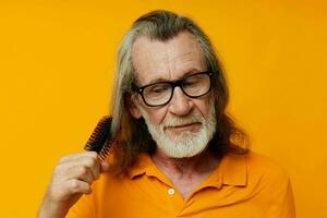 un anziano uomo con bicchieri pettini il suo lungo grigio capelli foto