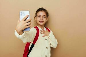 carino ragazza scolara zaino Telefono nel mano isolato sfondo foto