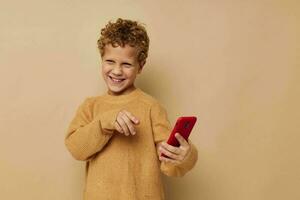 sorridente ragazzo nel un' maglione con un' Telefono nel il suo mani comunicazione foto