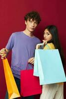 giovane ragazzo e ragazza nel colorato magliette con borse shopping isolato sfondo inalterato foto