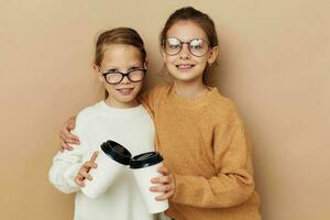 Due poco divertente ragazze un' bicchiere con un' bevanda beige sfondo foto