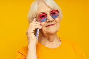 ritratto di un vecchio amichevole donna nel alla moda bicchieri con un' smartphone isolato sfondo foto