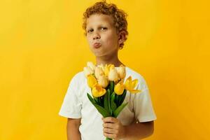 poco ragazzo Tenere un' mazzo di fiori un' regalo giallo sfondo inalterato foto