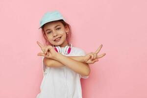 ritratto di contento sorridente bambino ragazza cuffie nel un' bianca maglietta e un' berretto stile di vita inalterato foto