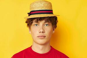 tipo con rosso Riccio capelli nel un' rosso maglietta con un' moda cappello giallo sfondo inalterato foto