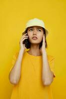 giovane donna nel un' giallo cappello gioventù stile casuale parlando su il Telefono isolato sfondo foto
