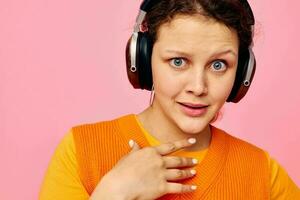 ritratto di un' giovane donna ascoltando per musica con cuffie arancia maglione emozioni divertimento isolato sfondi inalterato foto
