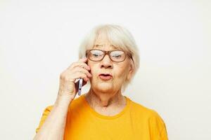 anziano donna nel un' giallo maglietta in posa comunicazione di Telefono avvicinamento emozioni foto