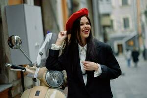 bellissimo donna Sorridi in piedi con un vecchio Vintage ▾ motociclo su un' città strada, elegante moda Guarda di Abiti, vacanza e viaggio. foto