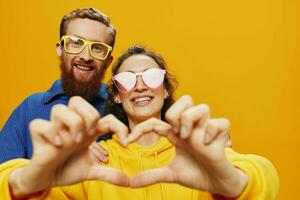 uomo e donna coppia sorridente allegramente e storto con occhiali, su giallo sfondo, simboli segni e mano gesti, famiglia sparare, Novelli sposi. foto